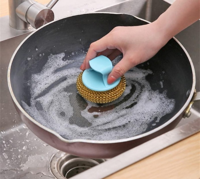 cleaning a frying pan with a hard sponge