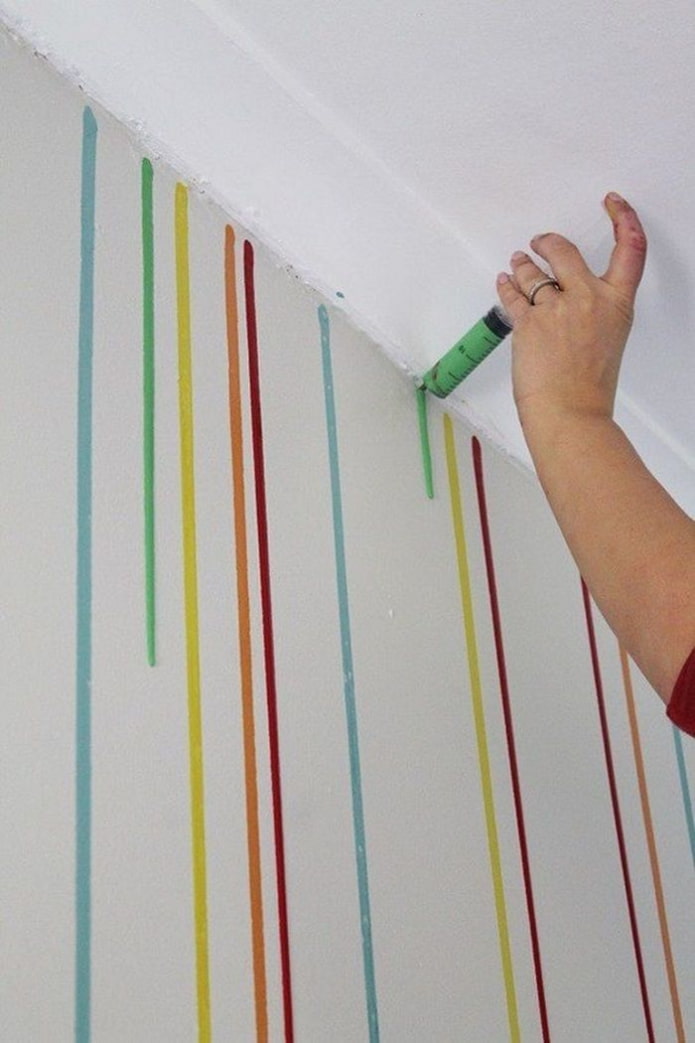 applying paint drips to the wall with a syringe