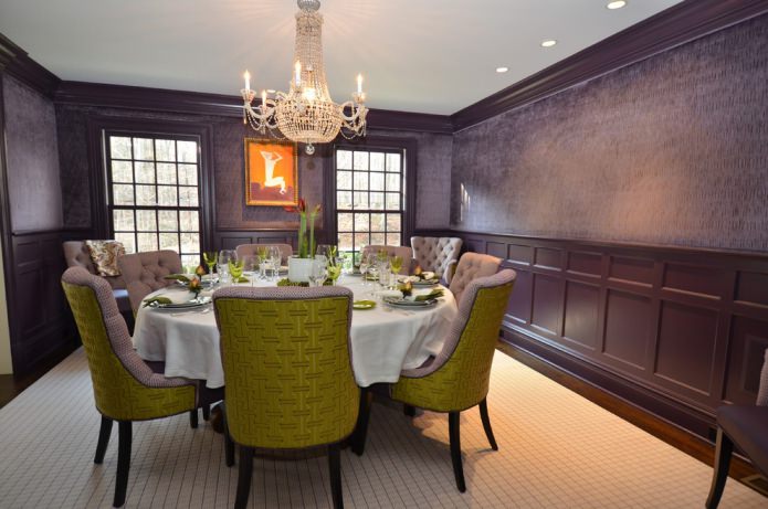 dining room with dark purple wallpaper and green and lilac chairs