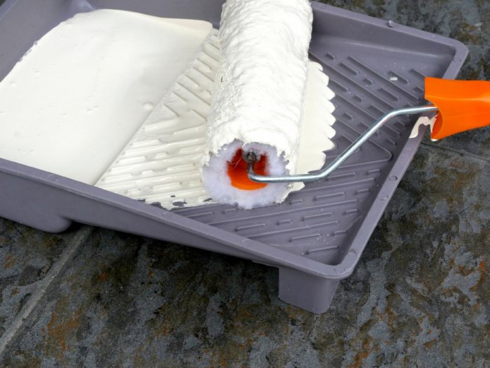Rolling the roller in a tray with paint