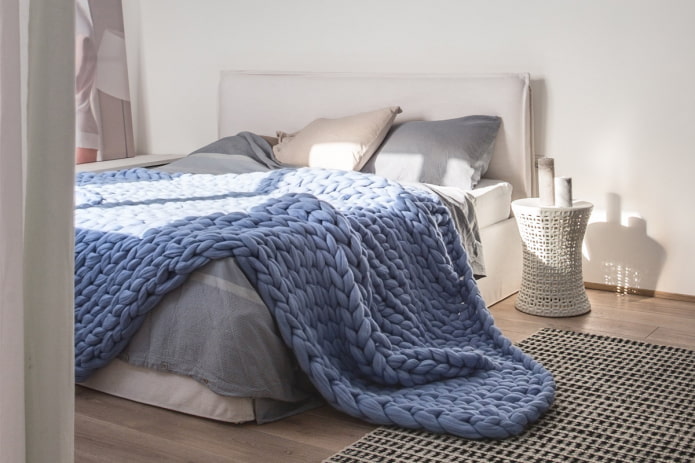 bed with a large knitted bedspread in the bedroom