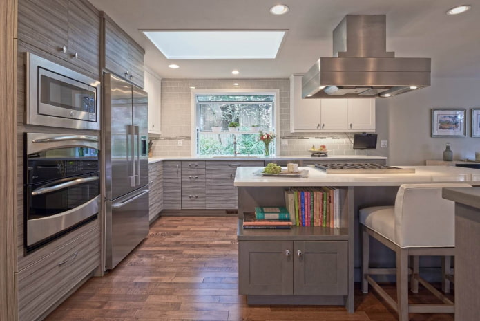 massive steel lamp and silver appliances in a gray and white kitchen