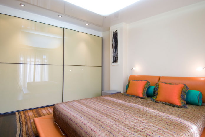 sliding wardrobe with a glossy facade in the bedroom interior