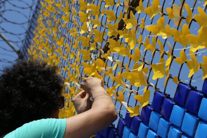 woman decorating a chain-link fence