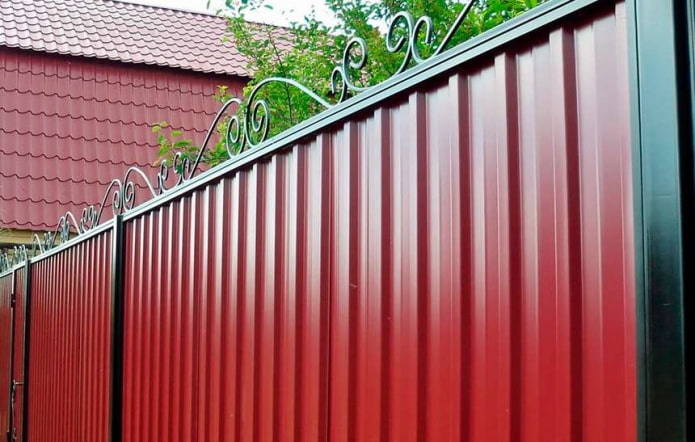 Red fence made of profiled sheet with forged elements