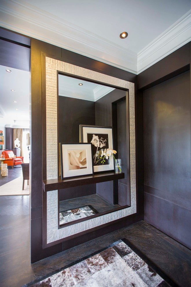 mirror with a shelf in the interior of the hallway